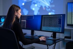 A woman analyzing cybersecurity logs on a desktop computer