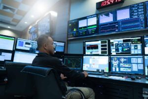 System Security Specialist Working at System Control Center looking at many computer monitors